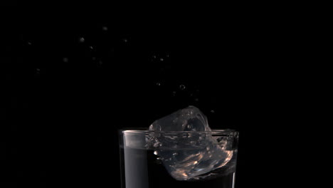 Eiswürfel-Fallen-In-Ein-Glas-Wasser-Auf-Schwarzem-Hintergrund