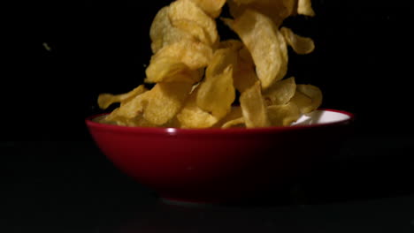 Chips-falling-into-bowl-on-black-surface