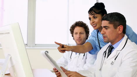 Doctors-sitting-at-desk-talking-about-xray-with-a-nurse