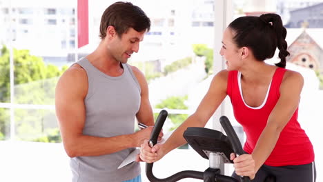 Fit-woman-working-out-on-exercise-bike-with-her-trainer