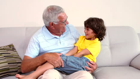 Senior-man-sitting-on-couch-with-his-grandson