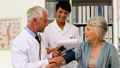 Médico-Tomando-La-Presión-Arterial-De-Su-Paciente-Con-Una-Enfermera-Presente