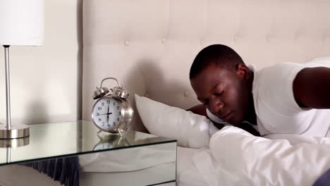 Man-waking-up-and-turning-off-his-alarm-clock