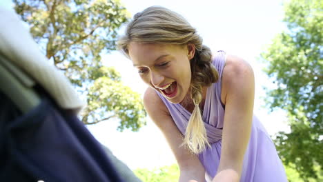 Mother-tending-to-her-baby-girl-in-her-pram-in-the-park