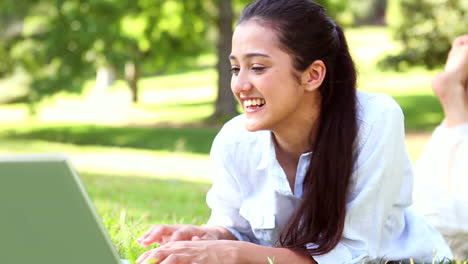 Pretty-girl-lying-on-the-grass-using-her-laptop