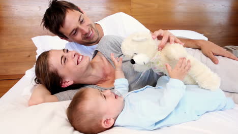 Happy-parents-lying-on-bed-with-baby-son