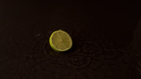 Lime-slice-spinning-on-wet-black-surface