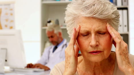 Ältere-Frau-Mit-Starken-Kopfschmerzen-Beim-Arztbesuch
