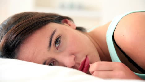 Unhappy-brunette-lying-in-bed-looking-at-camera