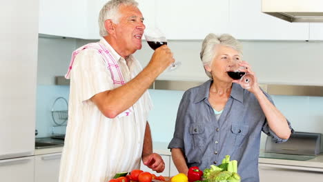 Senior-couple-preparing-a-healthy-meal-while-drinking-red-wine