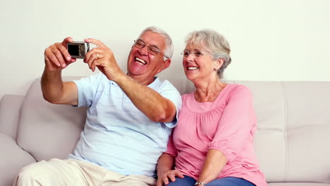 Happy-senior-couple-taking-a-selfie-on-the-couch