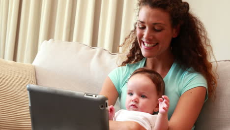 Mother-using-tablet-pc-for-video-chat-with-baby-son-on-her-lap