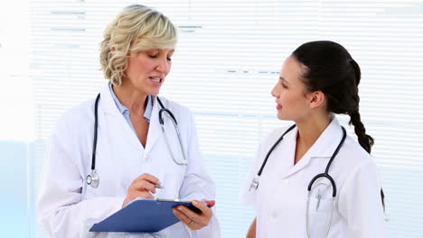 Doctor-and-nurse-discussing-something-on-clipboard