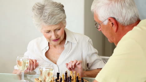 Senior-couple-sitting-at-table-playing-chess
