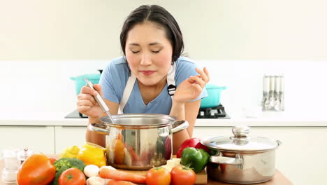 Happy-woman-stirring-pot-and-smiling-at-camera