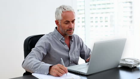 Casual-businessman-working-on-laptop-at-desk