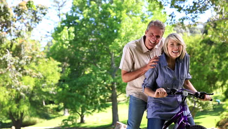 Happy-couple-posing-with-a-bike-in-the-park