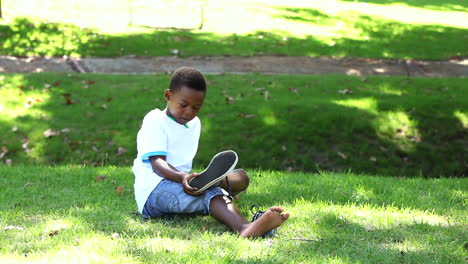 Niño-Sentado-En-El-Césped-Quitándose-Los-Zapatos