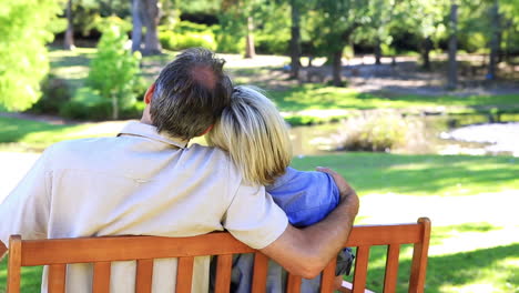 Affectionate-couple-sitting-on-park-bench