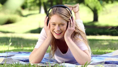 Niña-Feliz-Tumbada-En-Una-Manta-Escuchando-Música-En-El-Parque
