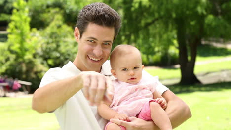 Happy-father-holding-his-baby-girl-in-the-park