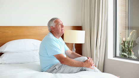 Senior-man-sitting-on-bed-thinking