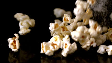 Popcorn-and-salt-pouring-onto-black-surface
