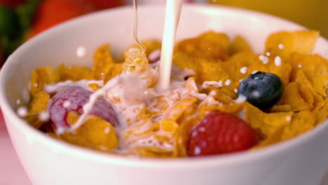 Milk-and-honey-pouring-into-bowl-of-cereal-with-berries