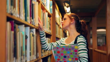 Estudiante-Concentrado-Escogiendo-Un-Libro-En-La-Biblioteca