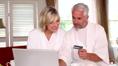 Happy-couple-shopping-online-in-bathrobes