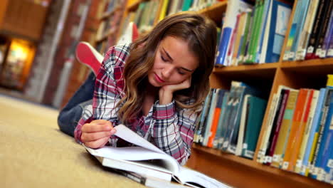 Bonito-Estudiante-Tumbado-En-El-Suelo-Leyendo-Un-Libro-En-La-Biblioteca.