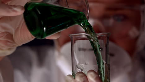 Scientist-pouring-green-liquid-into-beaker