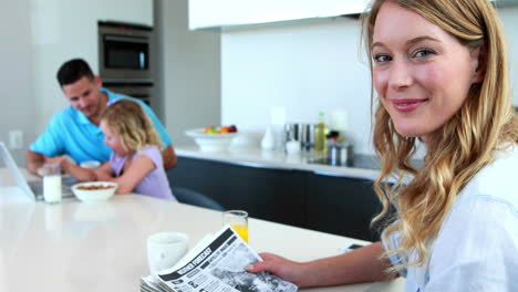 Mother-reading-the-paper-while-family-has-breakfast