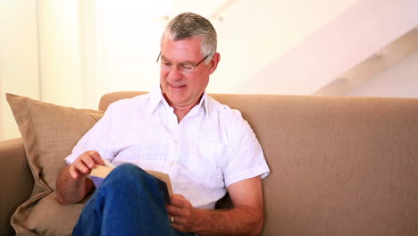 Happy-senior-man-sitting-on-the-couch-reading