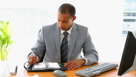 Hombre-De-Negocios-Trabajando-En-Su-Escritorio-Y-Escribiendo-En-El-Diario