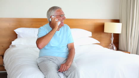 Senior-man-sitting-on-bed-talking-on-the-phone