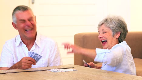 Senior-couple-sitting-on-floor-playing-cards