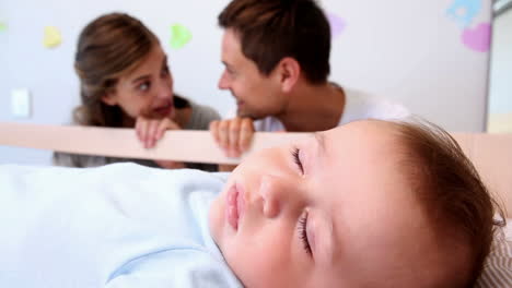 Glückliche-Eltern-Wachen-über-Ihren-Kleinen-Sohn-Im-Kinderbett-