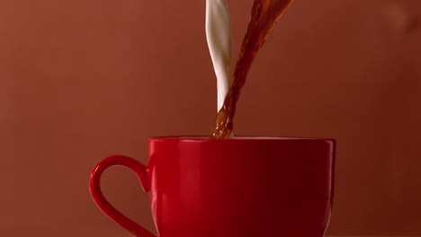 Hot-tea-and-milk-pouring-into-red-cup
