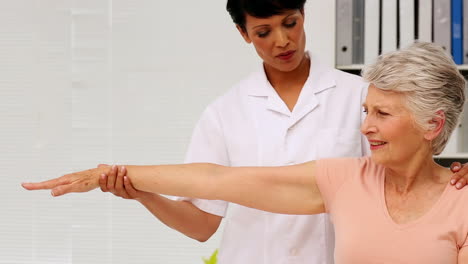 Enfermera-Mostrando-A-Un-Paciente-Anciano-Cómo-Ejercitar-Su-Brazo-Lesionado