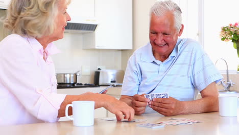 Senior-couple-sitting-at-counter-playing-cards