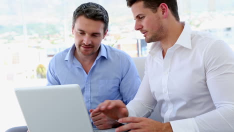 Businessmen-working-together-on-laptop