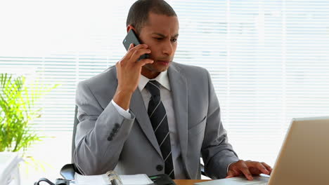 Businessman-answering-phone-at-his-desk