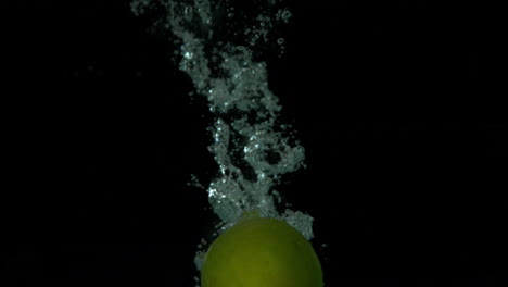 Manzana-Verde-Sumergiéndose-En-El-Agua-Sobre-Fondo-Negro