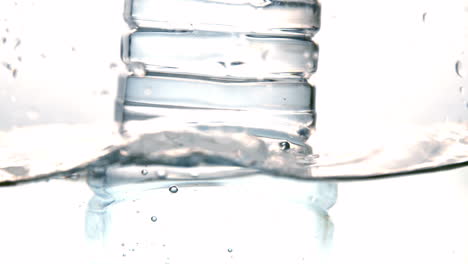 Botella-De-Plástico-Cayendo-Al-Agua-Sobre-Fondo-Blanco