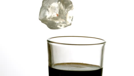 Ice-cube-falling-into-glass-of-soda