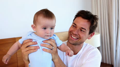Happy-father-sitting-with-baby-son-on-bed