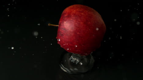Red-apple-falling-on-wet-black-surface