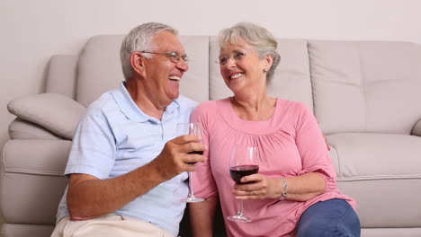 Senior-couple-sitting-on-floor-drinking-red-wine