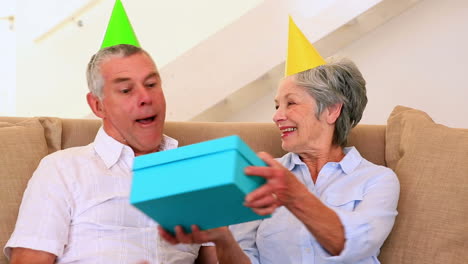 Senior-couple-sitting-on-couch-celebrating-a-birthday